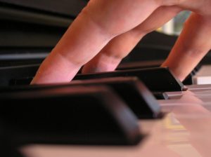 Hand on piano keys symbolizing adult Instruction 