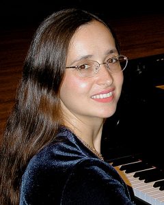 The Art of Piano Instructor Dr. Maria Horváth at a modern piano Instructor Dr. Horváth is posing at a modern piano
